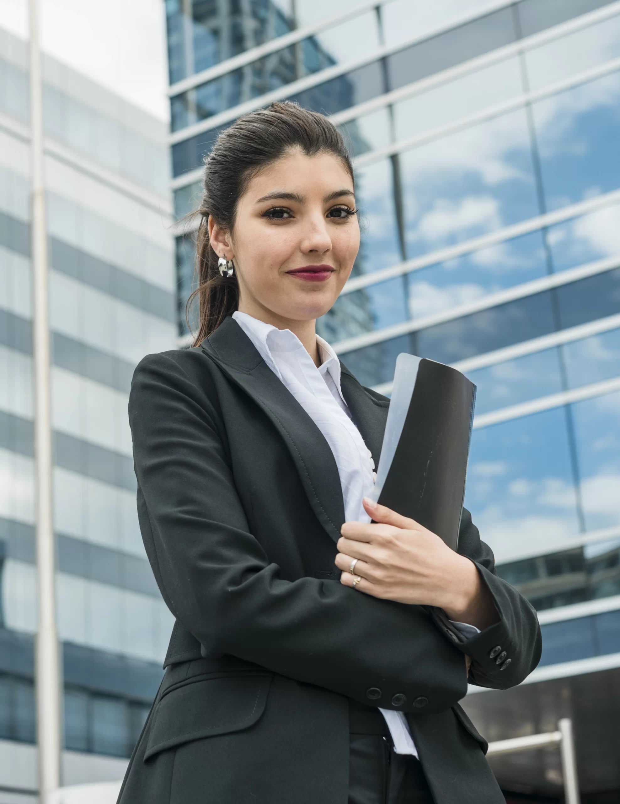 happy-young-businesswoman-holding-folder-standing-front-building